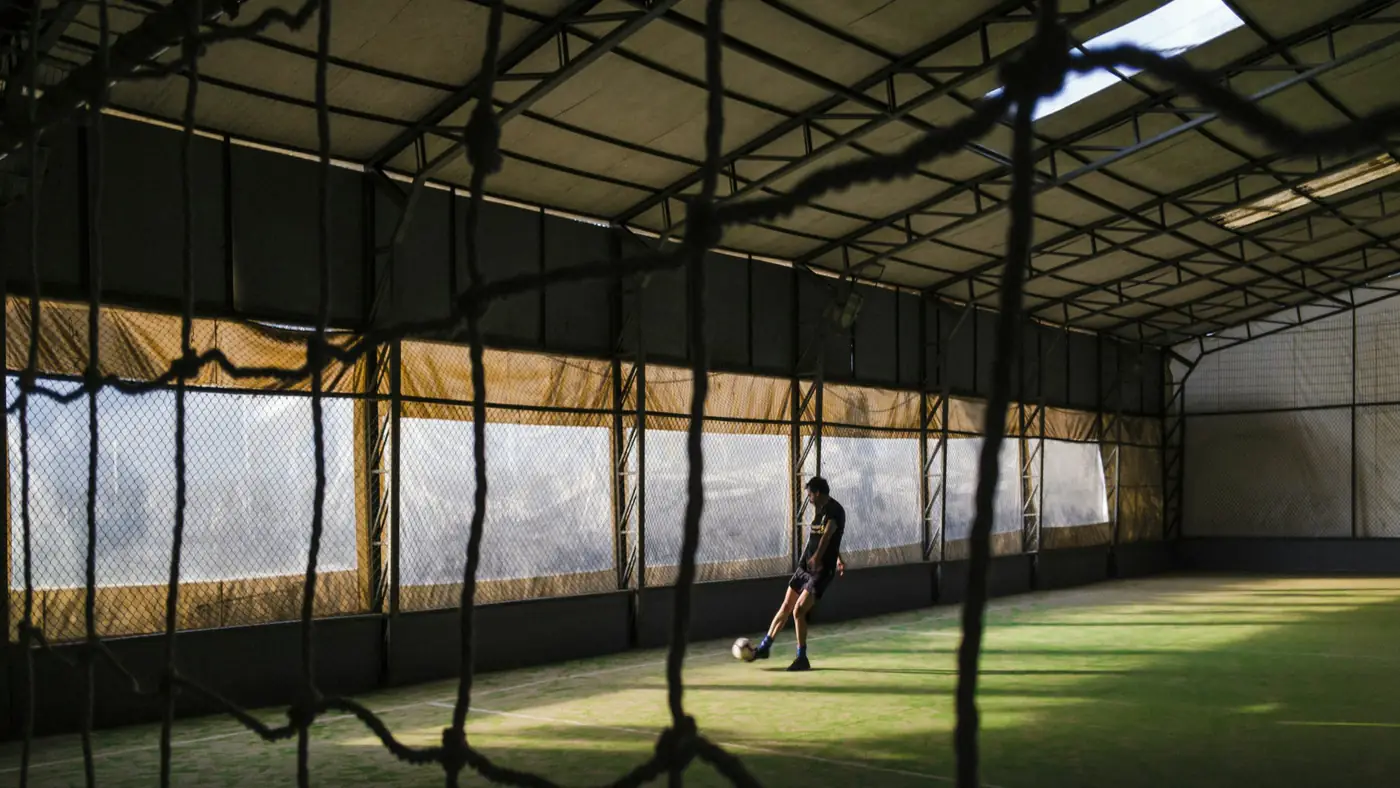 An indoor batting tunnel seen through netting.
